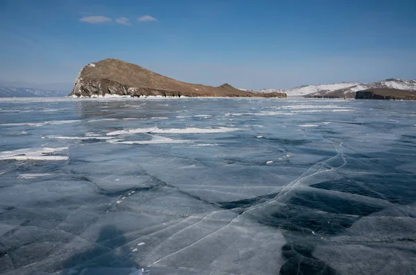 Vista da superfície de água coberta de gelo de formações de lago e rocha no fundo, Rússia, Lago Baikal — Fotografia de Stock