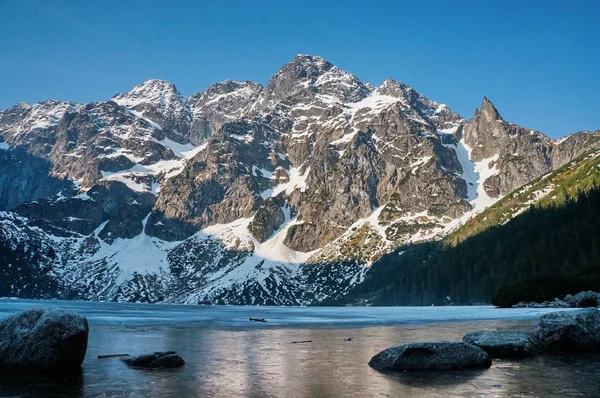 Vue sur les sommets enneigés des montagnes au-dessus de l'eau du lac, Morskie Oko, Sea Eye, Parc national des Tatra, Pologne — Photo de stock