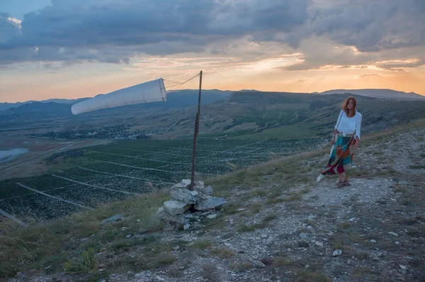 Woman walking in beautiful mountainous landscape with windsock waving in Crimea, Ukraine, May 2013 — Stock Photo