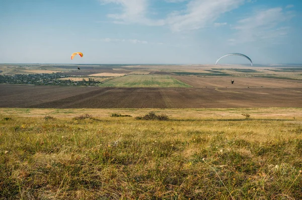 Parachutistes glissant dans le ciel bleu sur le paysage pittoresque de la Crimée, Ukraine, mai 2013 — Photo de stock