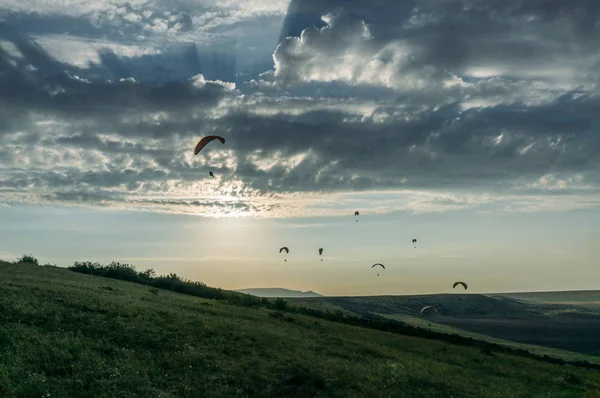 Fallschirme am Himmel über einem Feld in Hanglage der Krim, Ukraine, Mai 2013 — Stockfoto