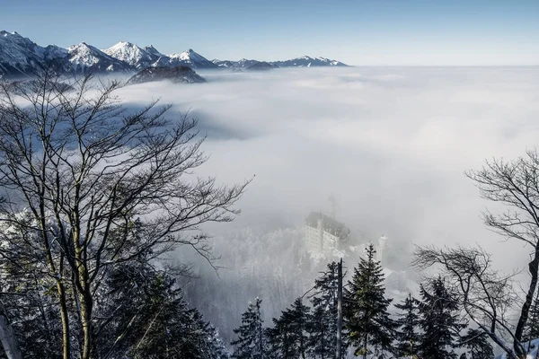 Vista panoramica delle montagne innevate nella nebbia vicino al castello di Neuschwanstein, Germania — Foto stock