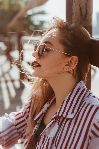 Retrato de cerca de la mujer joven con estilo sentado en el muelle de madera - foto de stock