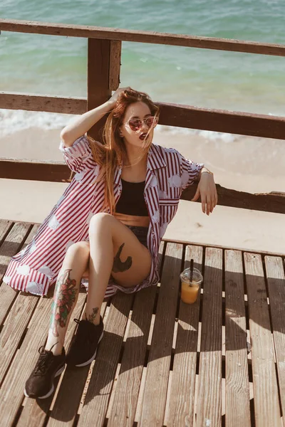 Sinnliche junge Frau sitzt auf dem Boden der Seebrücke am Strand — Stockfoto