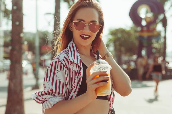 Attractive smiling woman drinking mango shake on sunny street — Stock Photo