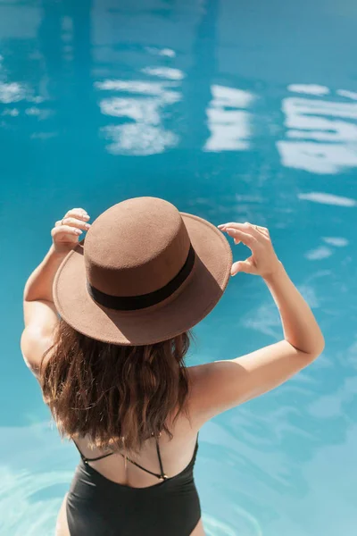 Belle jeune femme en maillot de bain et chapeau élégant à la piscine — Photo de stock