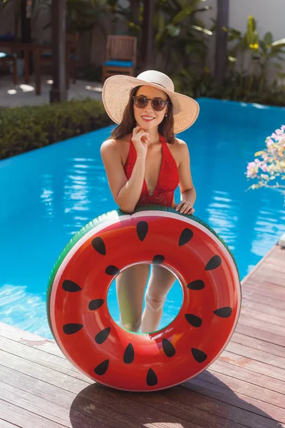 Schöne junge Frau im Badeanzug mit aufblasbarem Ring am Pool — Stockfoto