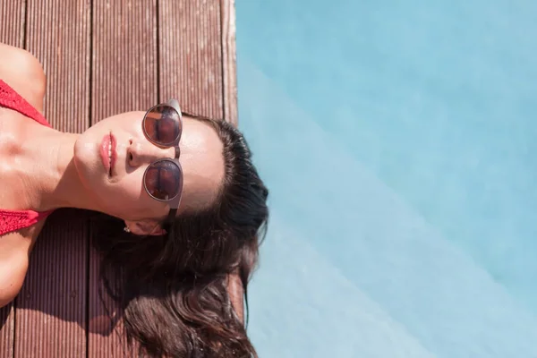 Vista superior da jovem mulher de biquíni deitada à beira da piscina — Fotografia de Stock