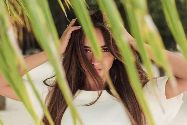 Selective focus of girl posing on beach with palm leaf — Stock Photo