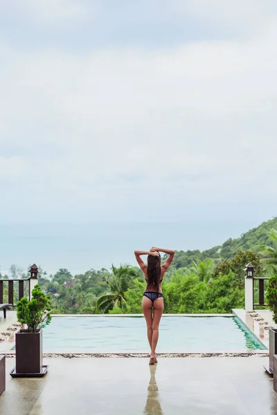 Rear view of girl posing at swimming pool on tropical resort — Stock Photo