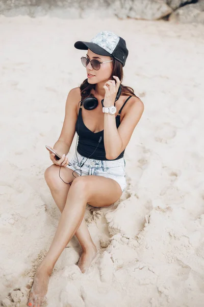 Mulher usando smartphone ouvindo música com fones de ouvido na praia — Fotografia de Stock