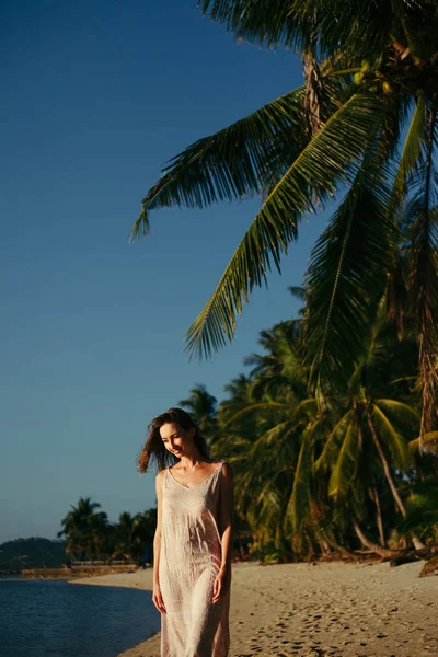 Mujer atractiva sonriente de pie en la playa del océano en el complejo tropical - foto de stock