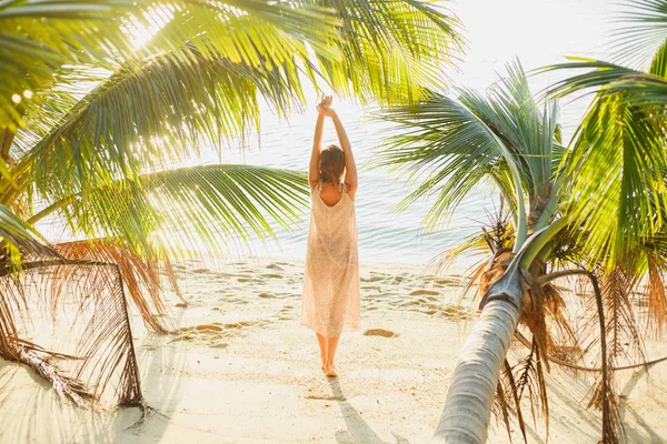 Задний вид женщины, растянувшейся между пальмами на берегу моря — стоковое фото
