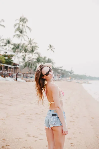 Hermosa chica posando en la playa y tocando el pelo - foto de stock