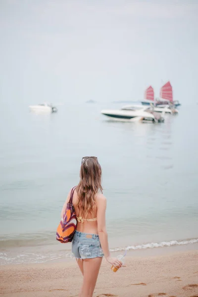 Rear view of woman holding cocktail and looking at boats in sea — Stock Photo