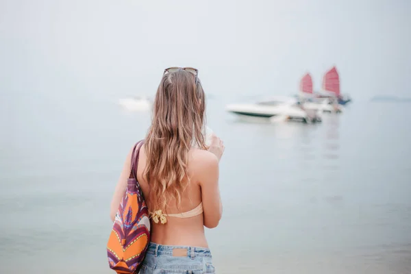 Vue arrière de femme boire cocktail et regarder les yachts dans l'océan — Photo de stock