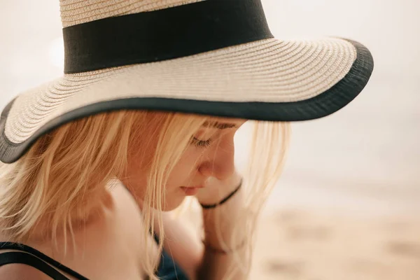 Side view of beautiful woman in hat on beach near ocean — Stock Photo