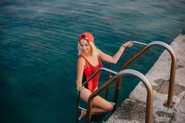 Schönes Mädchen im Badeanzug, das am öffentlichen Strand aus dem Meer steigt — Stockfoto