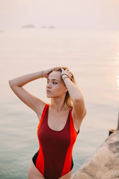 Beautiful girl posing in swimsuit near ocean and looking away — Stock Photo