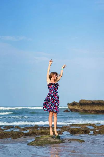 Happy young woman in dress jumping on beach — Stock Photo