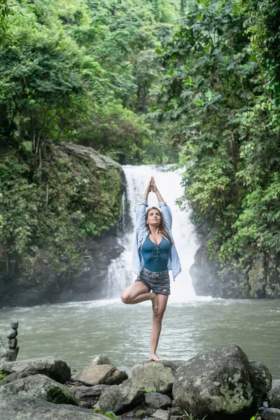 Attraente donna che pratica yoga con cascata Aling-Aling sullo sfondo, Bali, Indonesia — Foto stock
