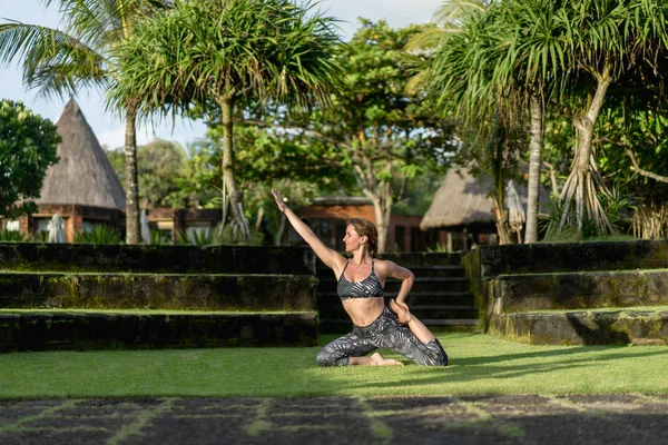 Mulher praticando ioga com belas plantas verdes no fundo, Bali, Indonésia — Fotografia de Stock