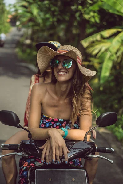 Happy young woman in sunglasses sitting on motorbike and smiling at camera — Stock Photo