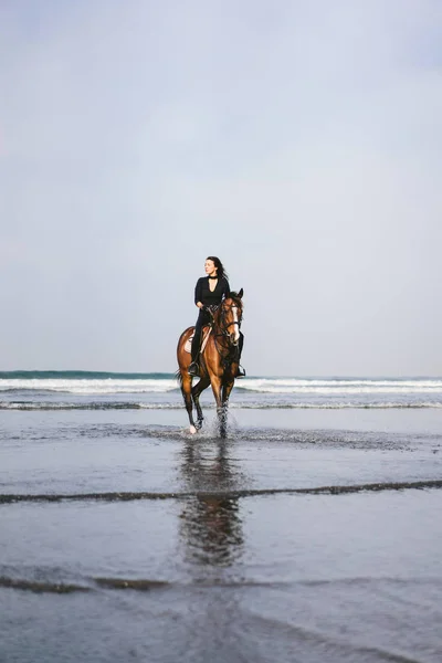 Vue de face de la jeune femme équitation cheval avec océan derrière — Photo de stock