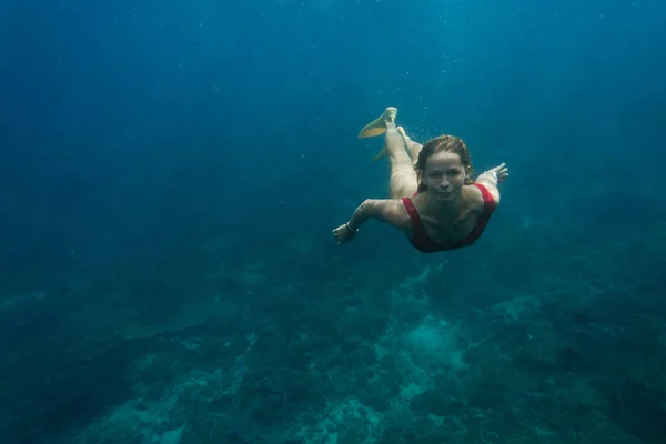 Foto subaquática de jovem mulher de fato de banho e nadadeiras mergulhando no oceano sozinho — Fotografia de Stock