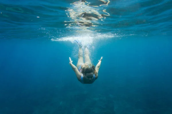 Underwater photo of young woman in swimming suit diving in ocean alone — Stock Photo