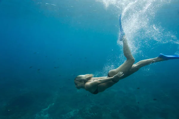 Side view of woman in bikini and flippers diving in ocean alone — Stock Photo