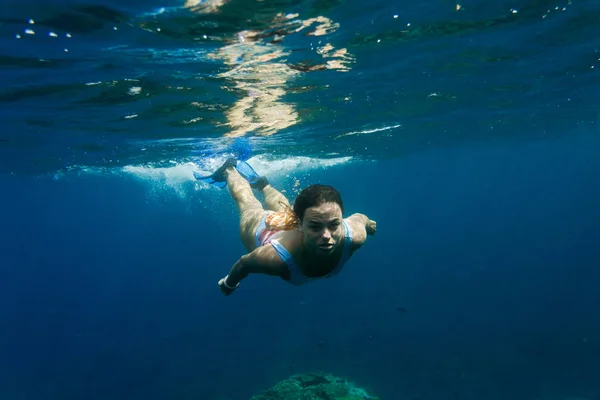 Underwater photo of young woman in swimming suit diving in ocean alone — Stock Photo