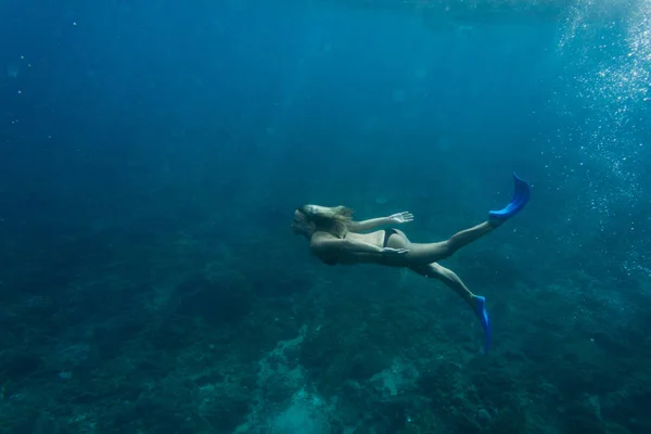 Side view of woman in bikini and flippers diving in ocean alone — Stock Photo