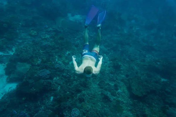 Unterwasserfoto eines jungen Mannes in Schwimmflossen, der allein im Ozean taucht — Stockfoto