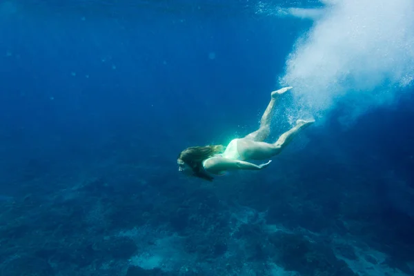 Underwater photo of young woman in swimming suit diving in ocean alone — Stock Photo