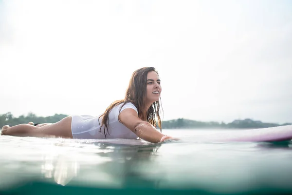 Attractive young woman swimming on surfboard in ocean — Stock Photo