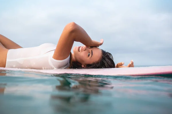 Beautiful young woman relaxing on surfboard in ocean during summer vacation — Stock Photo