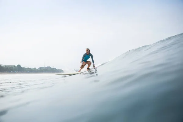 Attraktive junge Frau im sportlichen Badeanzug reitet Surfbrett im Ozean — Stockfoto