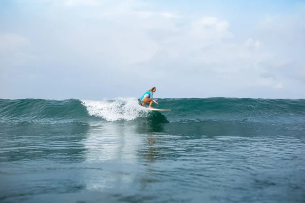 Atlética mujer joven en traje de baño deportivo montar tabla de surf en el océano durante las vacaciones de verano - foto de stock