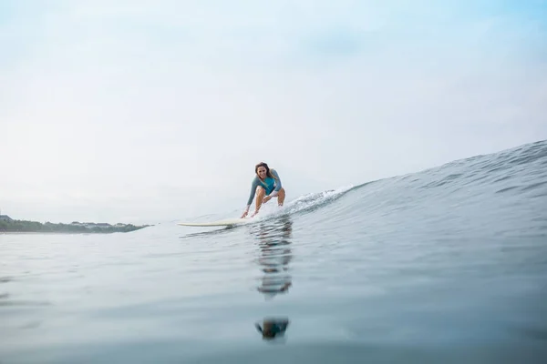 Atlética mujer joven en traje de baño deportivo montar tabla de surf en el océano durante las vacaciones de verano - foto de stock