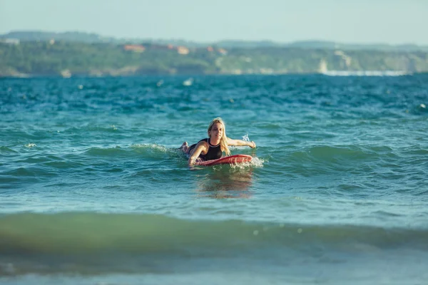 Beautiful sportswoman swimming on surfboard in water — Stock Photo