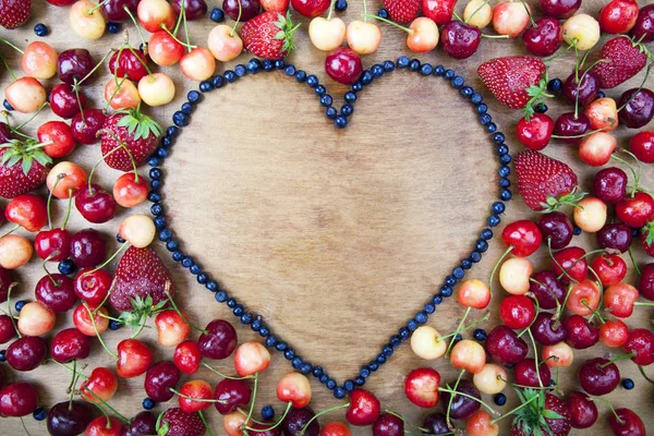 Many fresh fruit lying around the heart of blueberries — Stock Photo, Image