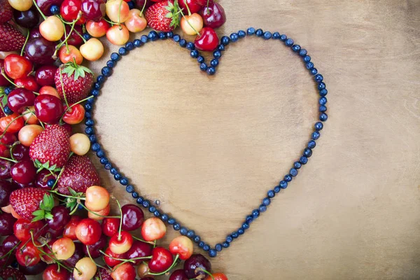 Many fresh fruit lying around the heart of blueberries — Stock Photo, Image