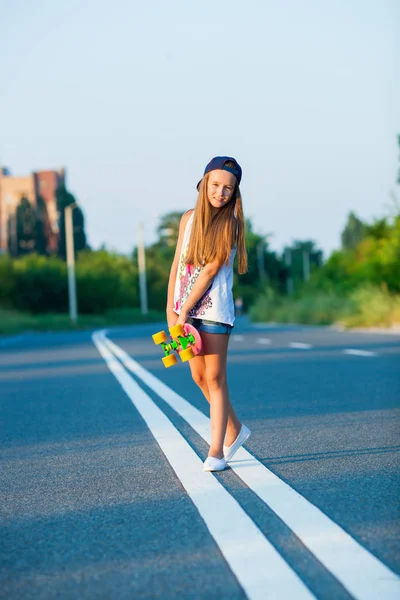 Une jeune fille avec un penny board en dehors de la ville — Photo