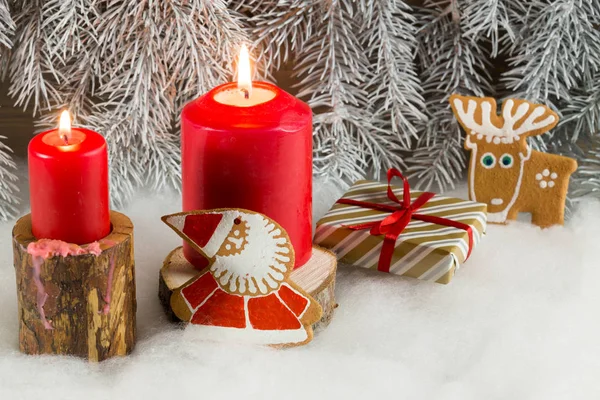 在浅雪的背景与冷杉树枝在木制的立场上有圣诞姜饼饼干 礼物和蜡烛 — 图库照片