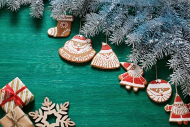 Ladin dalları, hediyeler, Noel kurabiyeleri ve yeşil ahşap arka planda süslemeler. kartpostallar için