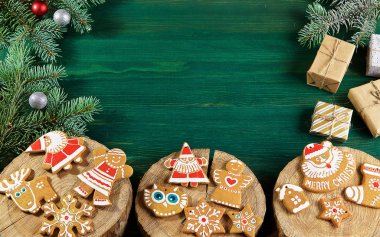 yeşil ahşap arka planda üzerlerinde ağacın kesikleri vardır zencefilli çörek ve ladin dalları vardır