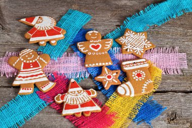 Noel kurabiyeleri, hediyeler ve köknar dalları gri ahşap arka planda ve renkli kumaş parçalarında