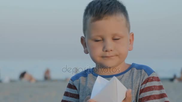 Junge hält Papierschiff in Händen und lächelt — Stockvideo