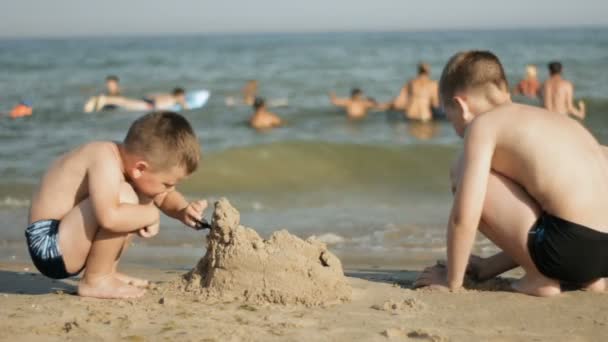 Jongens bouwen een zandkasteel — Stockvideo
